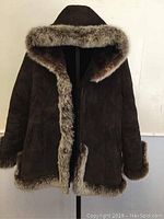 Front view of the brown suede coat highlighting the fox fur trim along the hood, front opening, cuffs, and hem.