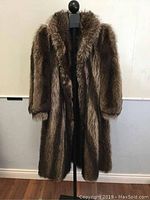 Front view of the full-length raccoon fur coat on a mannequin, showing its length, collar, and sleeve design.