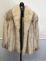 Front view of creamy tan Arctic fox fur jacket on stand
