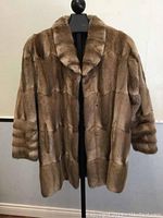 Front view of the muskrat fur coat on mannequin showing collar and sleeve detail.
