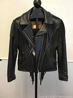 Front view of black leather jacket with fringe and purple accents