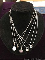 Front view of all 5 necklaces hanging on a black display stand showing overall look and pendants
