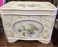 Front and part of side view of painted wooden box showing detailed floral painting and shape.