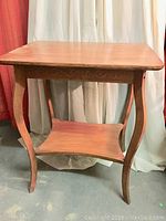 Full view of the vintage wood parlour table showing rectangular top, curved legs, and lower shelf.