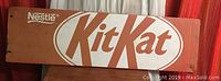 Front view of the entire Kit Kat metal sign mounted on a wall with visible wear and tear.