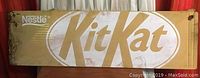 Front view of the vintage Kit Kat metal sign showing Nestle logo and large gold Kit Kat logo on distressed white metal.