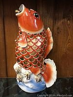 Front view of large ceramic koi fish figurine on wood background