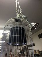 Chrome metal birdcage style ceiling light fixture with black interior shade hanging from a chain.