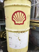 Photo of side of yellow metal barrel with red Shell shell logo and some wear and scratches.