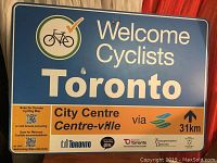 Full view of blue metal Toronto bicycle sign with directional and informational text and bicycle symbol.