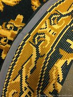 Close-up image showing the edge binding of the round rug and detailed pattern in gold and navy blue.