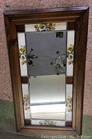 Full view of mirror showing wood frame and stained glass panels with floral motif