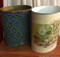 Pair of vintage metal trash cans shown side by side on a wooden surface, one with blue and green pattern and brass rim, the other with outdoor patio artwork.
