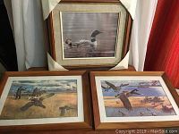 Three framed bird prints arranged with two on bottom and one above, showing waterfowl and flying birds in natural habitats.