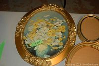 Oval gold ornate frame with floral print shown close-up