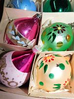 Close-up of six large vintage glass Christmas ornaments, featuring bright colors like pink, green, blue, and cream, with hand-painted floral and heart designs.
