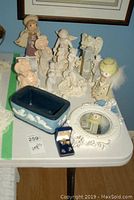 Photo of angel figurines, blue decorative container, pin earring set in blue box, and cream-colored ornate mirror