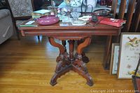 Full view of the wood table displaying many decorative items on top, showing scratches and chips on table surface.