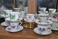 Photo of assorted decorative teacups and saucers with floral and gold detailing