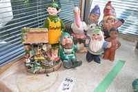 Photo of approximately 9 garden decor figurines including Canadian elf and various garden gnomes