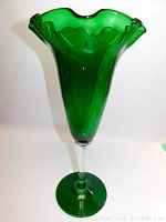 Green stemmed vase showing full profile with fluted wavy rim and clear stem and base.