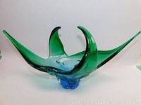 Murano glass sculpture with blue base and green elongated peaks, curved elegantly.