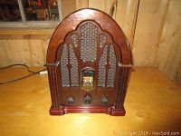 Front angled view of the vintage style GE radio, showing the wooden cabinet, fabric speaker grill, tuning display, and control knobs.