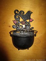 Front view of black cast iron bird planter with floral decoration and small bowl-shaped planter base