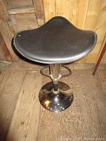 Front angle view of black adjustable stool with padded contoured seat and chrome base.