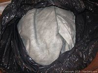 Grey soft fabric car cover folded inside a black plastic bag, showing textured surface and general condition.