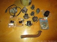 Photo showing a collection of vehicle parts including wiring, connectors, thermostat, and metal pipe.