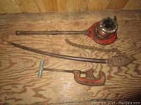 Full view of the pipe threading, bending and cutting tools laid on wooden surface