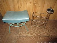 Photo of the vintage foot stool with a light blue padded seat and curved metal base, next to the smokers stand.
