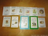 Overview photo showing 11 children's books by Beatrix Potter and A.A. Milne arranged on a flat surface.
