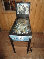 Front view of entire pinball machine including cabinet, legs and playfield