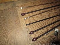 Curtain rods lying on wooden floor showing finials and rod details.