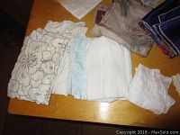 Photo showing various folded linens including embroidered and lace trimmed pieces