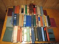 Photo of several rows of vintage hardcover books on a wooden surface showing varied titles and colors.