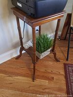 Full view of the wooden plant stand showing top, legs, and lower shelf with grass planter.