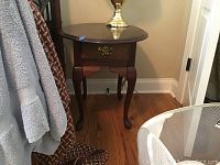 View of one wooden end table showing drawer, brass handle, cabriole legs, dark finish and wood grain detail
