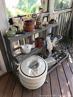 View of screen porch shelf with chicken and rooster statues, decorative candles, small plant pots, and a white Honeywell HEPA air cleaner at floor level.