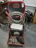 Front view of wheeled cart with coiled hose, storage container and spray gun