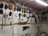 Pegboard wall with a row of baseball caps, level, squares and saw blades