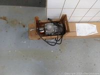 Motor unit with attached cables inside cardboard box placed on floor.