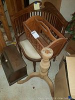Photo showing vintage wooden chair with curved back and upholstered seat, wooden magazine holder rack placed on seat, wooden breadbox on the floor, and wooden pedestal base next to chair.