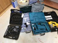 Full view of all tools in cases including Dewalt jigsaw, Makita drill, Hitachi nailer, Dremel tool and hand tools.