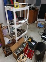 Plastic shelving unit with multiple woodworking tools and boxes on and around it, showing general contents of the lot.