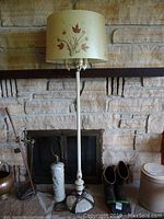 Full view of the vintage floor lamp assembled with lampshade standing against stone wall