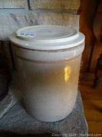 Side view of the large beige stoneware crock with lid, showing the cylindrical shape and neutral glaze finish.