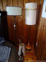 Three vintage floor lamps against wood panel wall, showing all lamps standing with cords visible